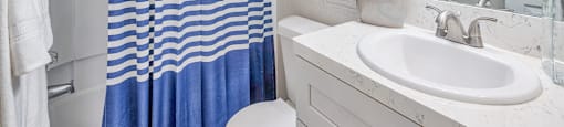 A white and blue bathroom with a white sink and a white toilet.