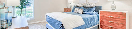 A bedroom with a bed, nightstand, and a ceiling fan.