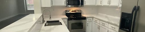 A modern kitchen with white cabinets and a stainless steel refrigerator.