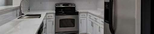 A modern kitchen with white cabinets and stainless steel appliances.