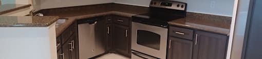 A kitchen with brown cabinets and a black stove top oven.