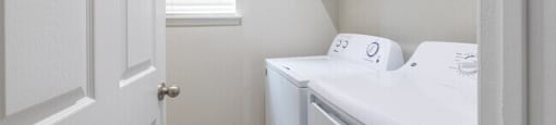 A white door is open to a laundry room with a washer and dryer.