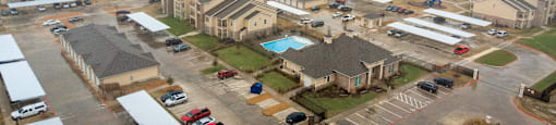 A large, modern housing complex with a swimming pool and parking area.