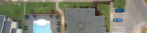 A swimming pool is surrounded by a grassy area and a building.