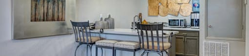 A kitchen with a bar stool and a painting on the wall.