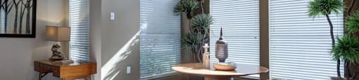 A room with a table, a plant, and a painting on the wall.