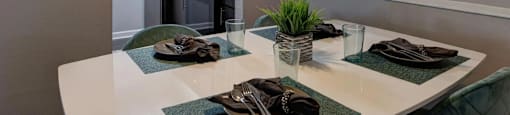 A modern dining area with a white table and green placemats.