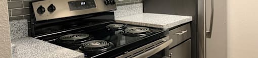 A kitchen with a black stove top oven and a black refrigerator.