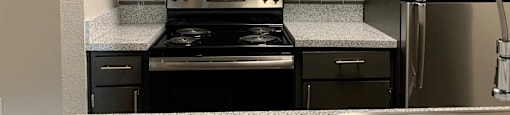 A modern kitchen with a stove, refrigerator, and cabinets.
