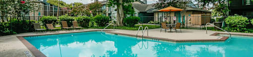 A swimming pool surrounded by trees and a building in the background.