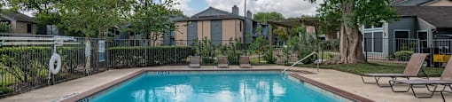 A swimming pool surrounded by trees and a fence.