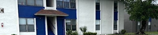 A white and blue building with a tree in front.