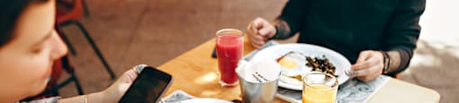 A person is sitting at a table with a plate of food and a glass of juice.