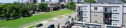 A cityscape with a building in the foreground and a highway in the background.