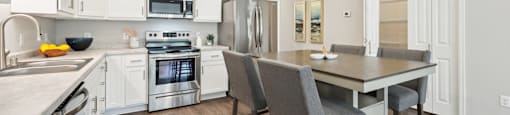 a kitchen and dining room with white cabinets and stainless steel appliances