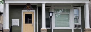 A two story house with a front porch and a yellow door.