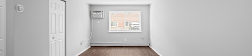 the living room is empty and has white walls and wood floors