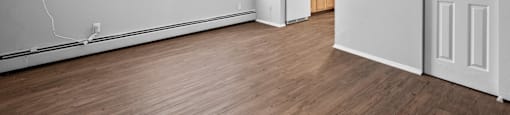 the living room and kitchen of an apartment with wood flooring and white walls