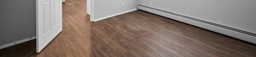 the living room and dining room of an apartment with wood flooring and a window