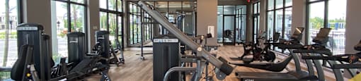 a gym with cardio equipment and windows in a building