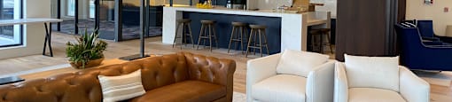 a living room with a couch and chairs and a kitchen