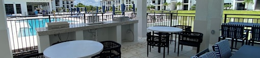 a patio with tables and chairs overlooking a swimming pool