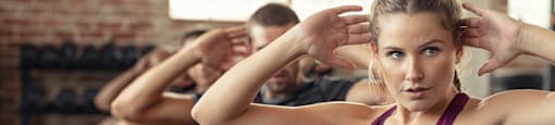 a group of young people in a gym doing exercises with their hands on their heads