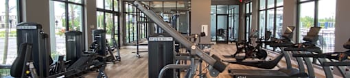a gym with treadmills and other exercise equipment on a wood floor