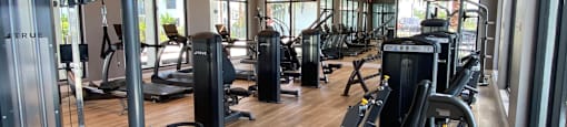 a gym with cardio machines and weights on a wooden floor