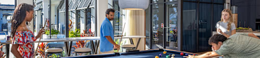 A group of people playing pool in a brightly lit room.