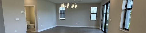 A large, empty room with a rug on the floor and a chandelier hanging from the ceiling.