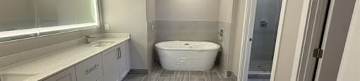 A bathroom with a tub, sink, and a walk-in shower.