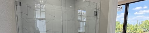 A bathroom with a walk-in shower and a glass door.