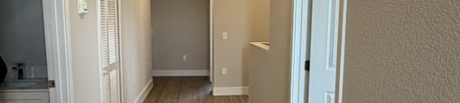 A long, narrow hallway with wood flooring and white walls.