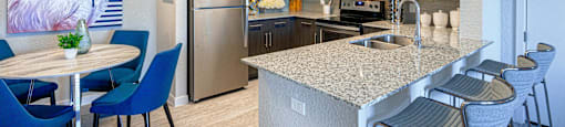 a kitchen with a large island with granite countertops and dark wood cabinets