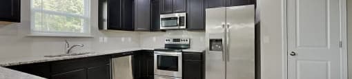 A kitchen with black cabinets and stainless steel appliances.