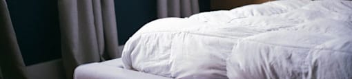 a bed with a white comforter and pillows on it