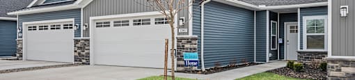 A house with a tree in front and a sign that says Welcome Home.