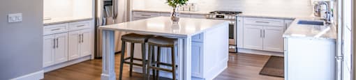 a kitchen with white cabinetry and a large center island with a white countertop
