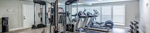 a gym with treadmills and other exercise equipment in a room with a mirror
