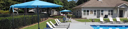 a swimming pool and patio with chairs and umbrellas