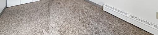 A room with a carpeted floor and a white wall with a doorway leading to another room.