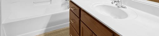 A bathroom with a white sink and a white tub/shower.