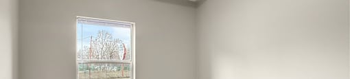 A bedroom room with a grey carpet and a window looking outside