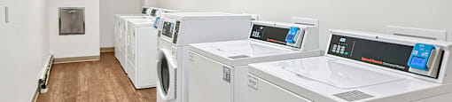 A row of white front load washing machines in a laundromat.