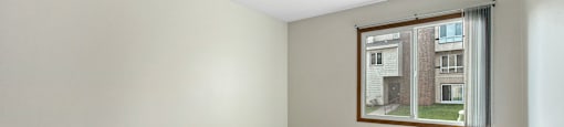 A room with a window showing a view of a building outside.