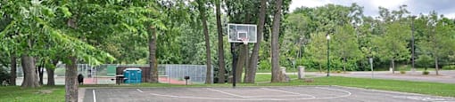 A basketball court surrounded by trees in a park.