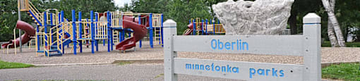 A sign for Minnetonka Parks stands in front of a playground.