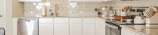 A kitchen with white cabinets and a black fridge.