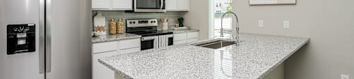 A kitchen with a granite countertop and stainless steel appliances.
